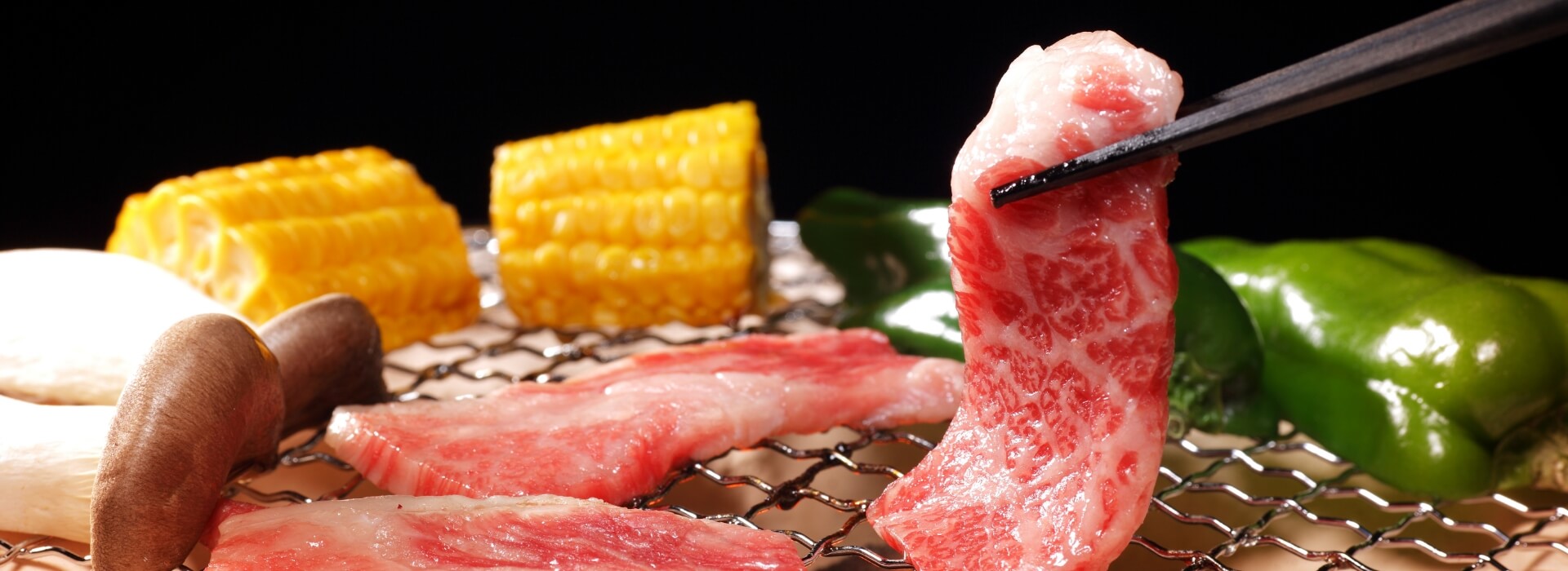 網の上で野菜と一緒に焼かれる但馬牛のお肉